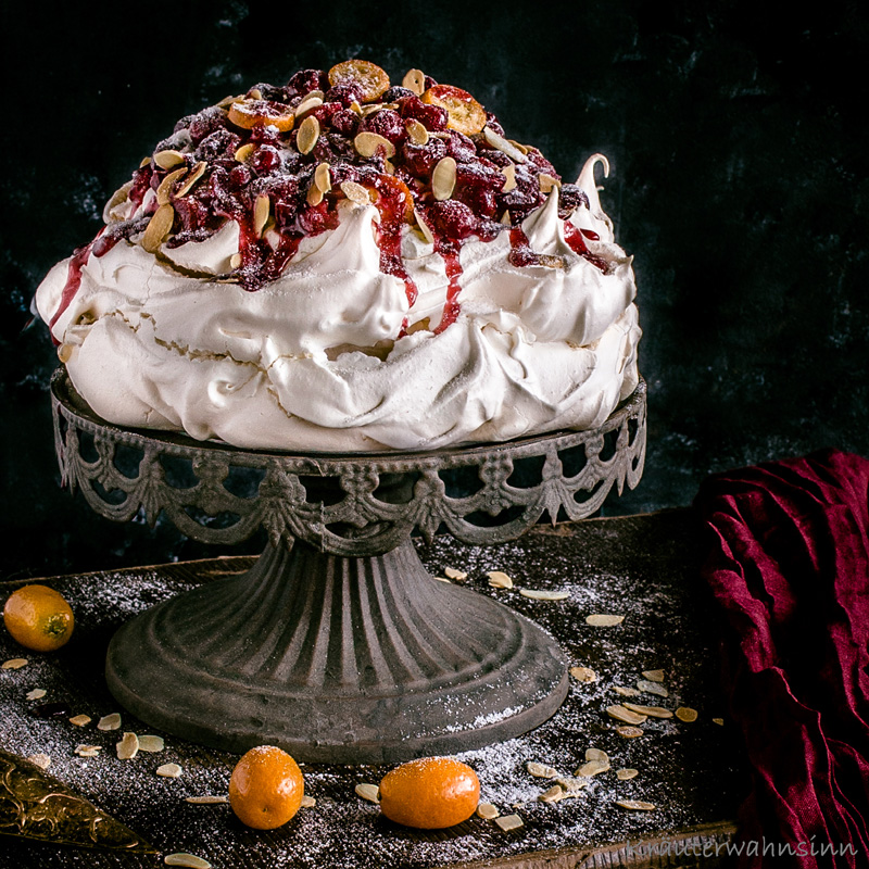 Winter-Pavlova mit gebackenen Cranberries und Kumquats auf Vanille-Sahne